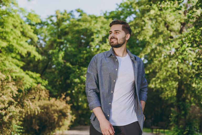man calmly walking in nature with a smile on his face