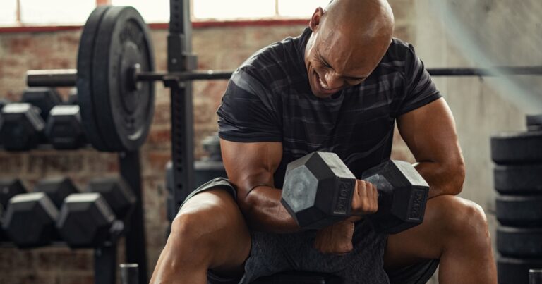 muscular man curling heavy dumbbell