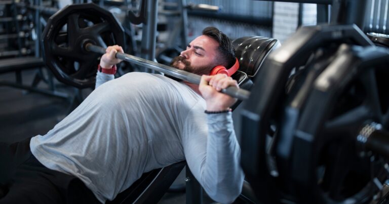 man on the incline bench press lifting a heavy barbell