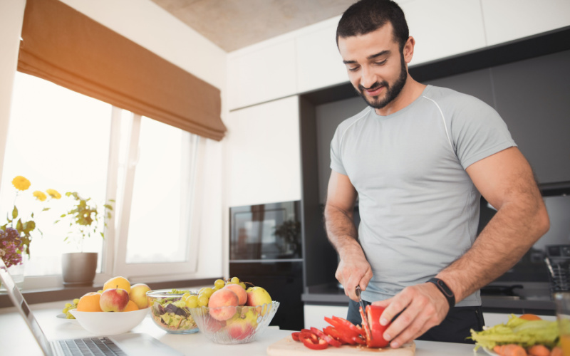 athletic man cutting fruits and vegetables