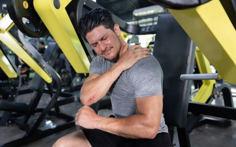 man at the gym holding shoulder in pain