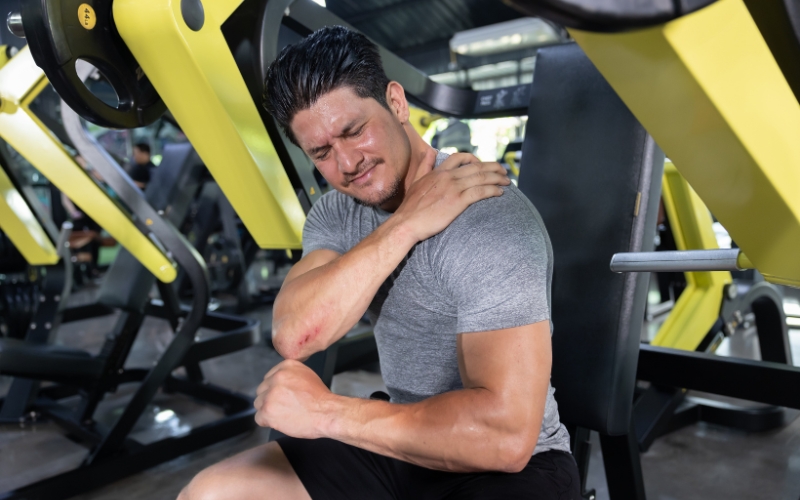 man at the gym holding shoulder in pain