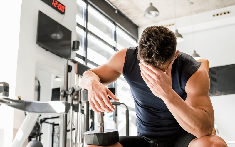 tired man in the gym with his head down tired man in the gym with his head down